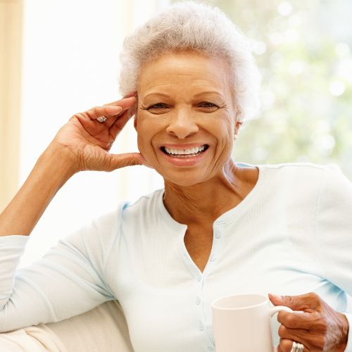 older female speech therapy client smiling while drinking coffee