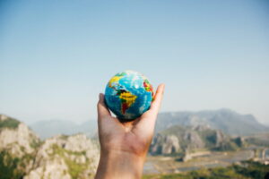 hand-holding-small-globe-in-front-of-mountain-background